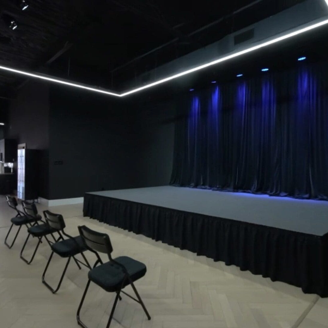 Empty stage with chairs arranged in front in a dark room.